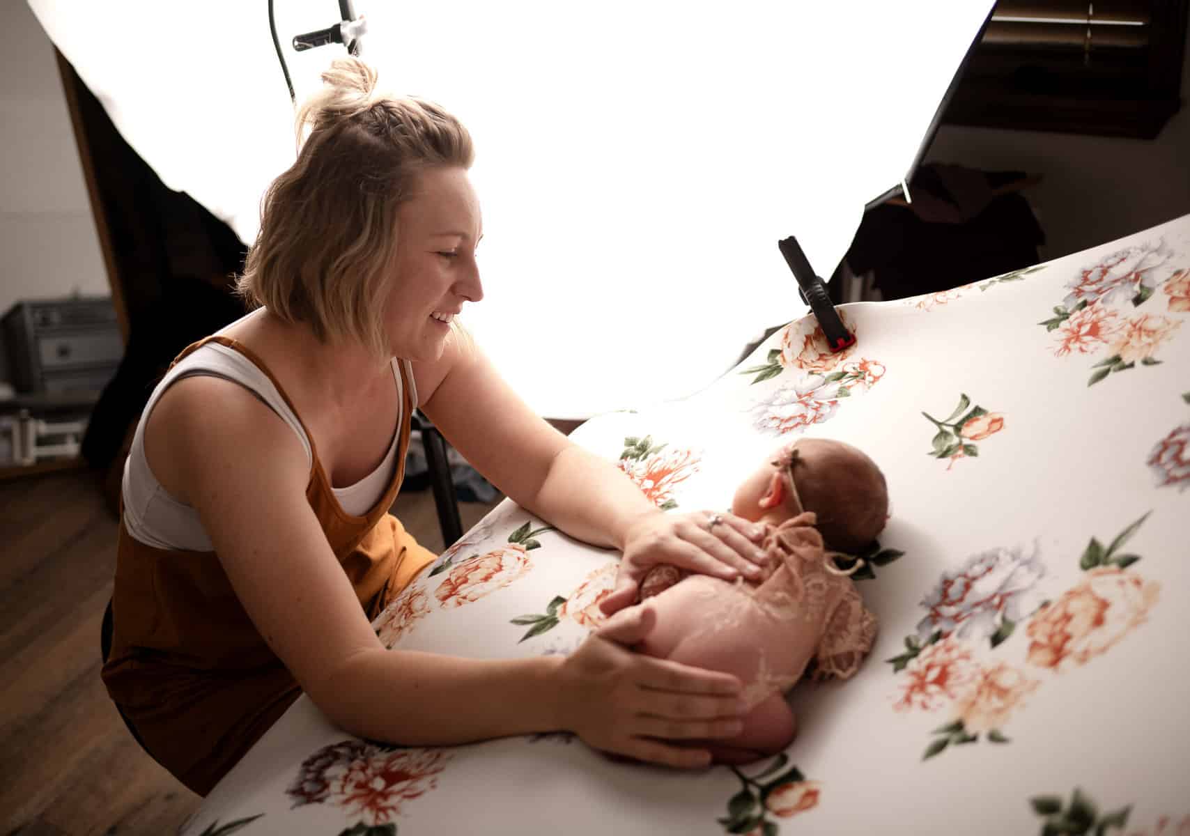 wichita photographer newborn specialist sara with sj nuzum photography works on posing a baby for a photo session