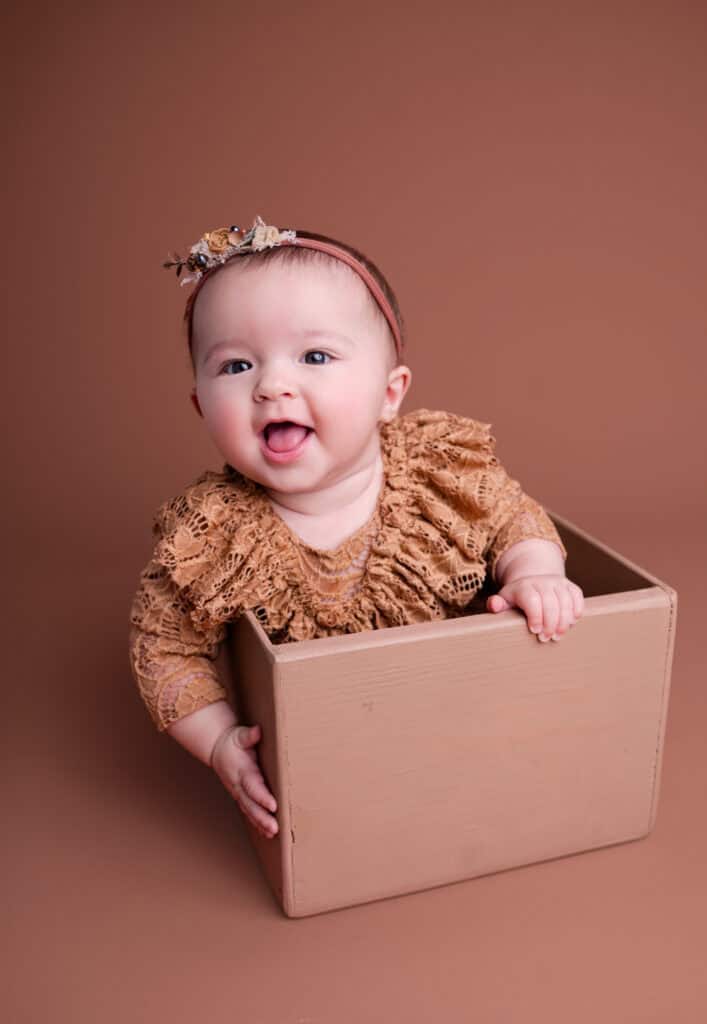 family photographer wichita ks baby smiles in a box in a beautiful lace outfit