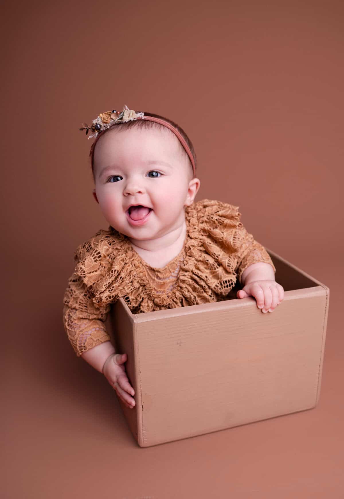 family photographer wichita ks baby smiles in a box in a beautiful lace outfit