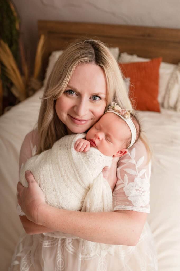 mom smiles holding new baby girl for newborn photos SJ Nuzum Photography